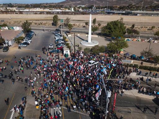 A group of migrants gather at the Chaparral border crossing in Tijuana, Mexico, Sunday, Nov. 25, 2018, as they try to pressure their way into the U.S. The mayor of Tijuana has declared a humanitarian crisis in his border city and says that he has asked the United Nations for aid to deal with the approximately 5,000 Central American migrants who have arrived in the city. [Photo: AP/Rodrigo Abd]