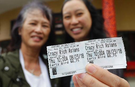 In this Thursday, Aug. 23, 2018 photo, Audrey Sue-Matsumoto, right, holds tickets as she poses for photos with her mother Alice Sue while interviewed outside of a movie theater after watching the movie Crazy Rich Asians in Daly City, Calif. It was Alice Sue's second time watching the movie. When